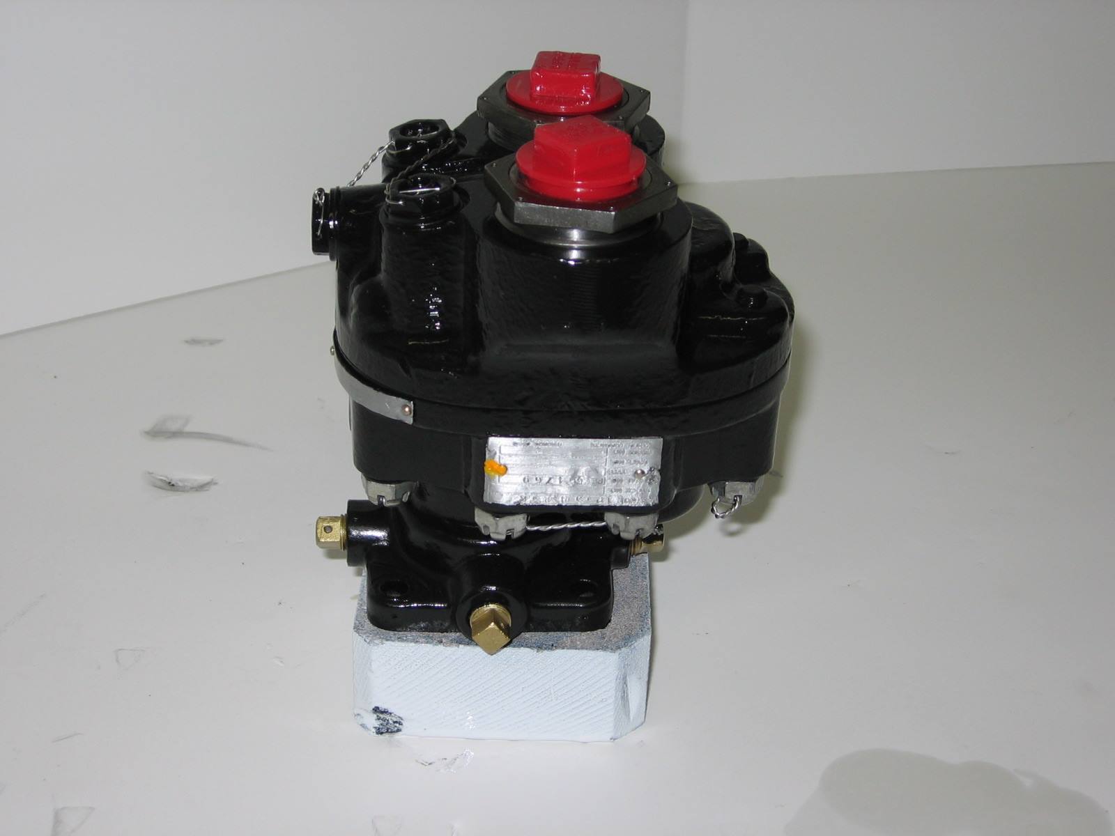 Black PESCO aircraft hydraulic pump with red protective caps mounted on a white foam block against a white background